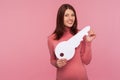 Happy brunette woman in pink sweater holding big paper key and looking at camera with toothy smile, apartment purchase Royalty Free Stock Photo