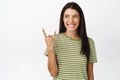 Happy brunette woman shows rock on, heavy metal gesture, smiling and looking aside at event announcement, standing over