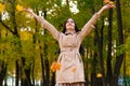 Happy brunette woman throws up autumn leaves up