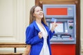 Happy brunette woman withdrawing money from credit card at ATM