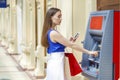 Happy brunette woman withdrawing money from credit card at ATM