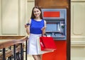 Happy brunette woman withdrawing money from credit card at ATM