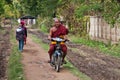 A happy Buddhist monk driving a motorbike on a village street