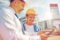 Happy builders in hardhats with tablet pc outdoors Royalty Free Stock Photo