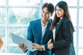 Happy business couple standing together  checking work on laptop near the window background. Royalty Free Stock Photo