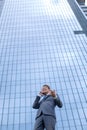 Happy business man with smartphone standing in front of high rise office building Royalty Free Stock Photo