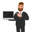 Happy business man in suit holding or showing the blank screen of a laptop computer and pointing hand finger. Hipster male. Royalty Free Stock Photo