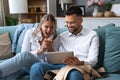 Happy business man and woman sitting on sofa at home holding tablet rejoicing and celebrating their company stock price jump in Royalty Free Stock Photo