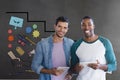 Happy business men holding a tablet against grey background with graphics Royalty Free Stock Photo