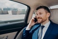 Happy business owner sitting on back seat in car and talking on phone Royalty Free Stock Photo