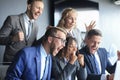 Happy business people laugh near laptop in the office. Successful team coworkers joke and have fun together at work. Royalty Free Stock Photo