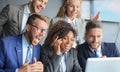 Happy business people laugh near laptop in the office. Successful team coworkers joke and have fun together at work. Royalty Free Stock Photo