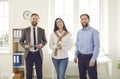 Team of three cheerful young business people standing in their office and smiling Royalty Free Stock Photo