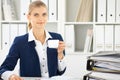 Happy business woman or female accountant having some minutes for coffee and pleasure at working place Royalty Free Stock Photo