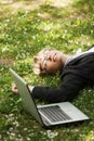 Happy business woman with laptop lying on the grass Royalty Free Stock Photo