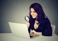 Happy business woman with magnifying glass looking at laptop computer sitting at desk Royalty Free Stock Photo