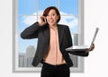 Happy business woman with red hair talking on the mobile cell phone holding computer laptop in hand multitasking Royalty Free Stock Photo