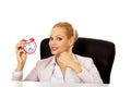 Happy business woman sitting behind the desk and holding alarm clock Royalty Free Stock Photo