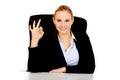 Happy business woman sitting behind the desk and shows OK sign Royalty Free Stock Photo
