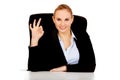 Happy business woman sitting behind the desk and shows OK sign Royalty Free Stock Photo