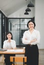 Happy business woman standing competently and smiling in open plan office