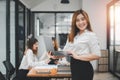 Happy business woman standing competently and smiling in open plan office