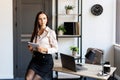 Happy business woman using pen and writing something in her notebook, raising her hand up, showing a greeting gesture Royalty Free Stock Photo