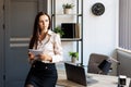 Happy business woman using pen and writing something in her notebook, raising her hand up, showing a greeting gesture Royalty Free Stock Photo