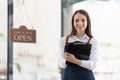 Happy business woman is a waitress in an apron, the owner of the cafe stands at the door with a sign Open waiting for Royalty Free Stock Photo