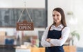 Happy business woman is a waitress in an apron, the owner of the cafe stands at the door with a sign Open waiting for Royalty Free Stock Photo