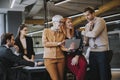 Happy business women working together online on a digital tablet in front of young team at the office Royalty Free Stock Photo