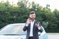 Happy businessman car salesman inspects the car online with a video call, and an application on the phone, a man has fun selling a