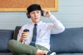 Happy businessman enjoy listening favorite music from wireless earphone with dance acting along song rhythm and drinking cup of