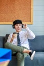 Happy businessman enjoy listening favorite music from wireless earphone with dance acting along song rhythm and drinking cup of