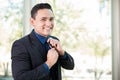 Happy businessman fixing his tie