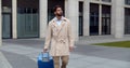 Happy businessman going on business trip walking outside with travel suitcase Royalty Free Stock Photo