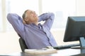 Happy Businessman With Hands Behind Head Looking Up In Office