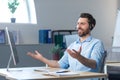 Happy businessman with headset for video call working in modern office, smiling man looking at computer monitor Royalty Free Stock Photo