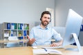 Happy businessman with headset for video call working in modern office, smiling man looking at computer monitor Royalty Free Stock Photo