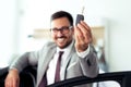 Happy businessman holding keys to her new car at the dealership Royalty Free Stock Photo