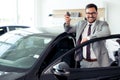Happy businessman holding keys to her new car at the dealership Royalty Free Stock Photo