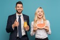 Happy businessman with orange juice showing thump up near smiling businesswoman with juicy watermelon Royalty Free Stock Photo