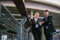 Happy businessman showing content on tablet to female colleague. Business man and woman walking outside using tablet and talking, Royalty Free Stock Photo