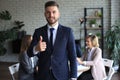 Happy businessman showing his thumb up with colleagues in the background in office Royalty Free Stock Photo