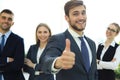 Happy businessman showing his thumb up and smiling while his colleagues standing in the background Royalty Free Stock Photo