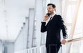 Happy businessman standing in airport, talking on phone Royalty Free Stock Photo