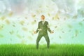 A happy businessman standing on a green lawn with a rain of dollar bills falling upon him from the cloudy sky. Royalty Free Stock Photo