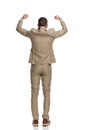 Happy businessman in suit holding arms above head and cheering
