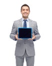 Happy businessman in suit showing tablet pc screen