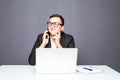 Happy young businessman talking on cell phone and using laptop in office Royalty Free Stock Photo